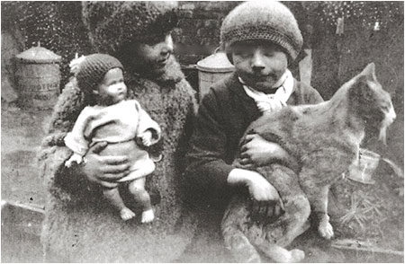 Photograph of Joan wearing her astrakhan coat and hat together with her friend, Kath Lewis holding the cat