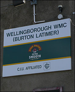 Photograph of a sign on the side of the club bearing the words"Wellingborough WMC (Burton Latimer)".