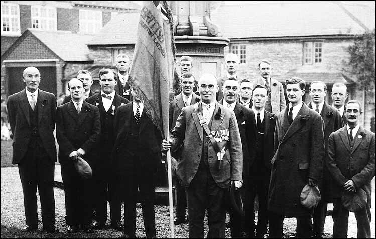 British Legion Members with banner dedicated at the Armistice Commemoration Service in 1930.  At the back of the group with medals is Mr Hancock.  At the front from L to R: Billy Brace (with cap), William Lovell (bow tie), standard bearer Jim Bull, Bob Phillips, Bernard Clipson, Mr F W Tailby, Mr C R Blissett (holding cap), behind him Jack Dacre and behind him Harry Craddock