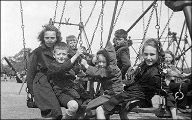 Photograph of the same excursion, with the children enjoying a ride on the swings.