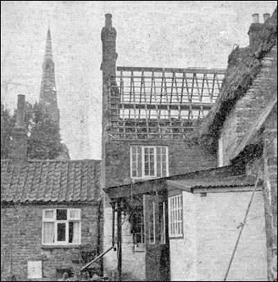 Photograph showing thatched roof of shop partially destroyed by fire.